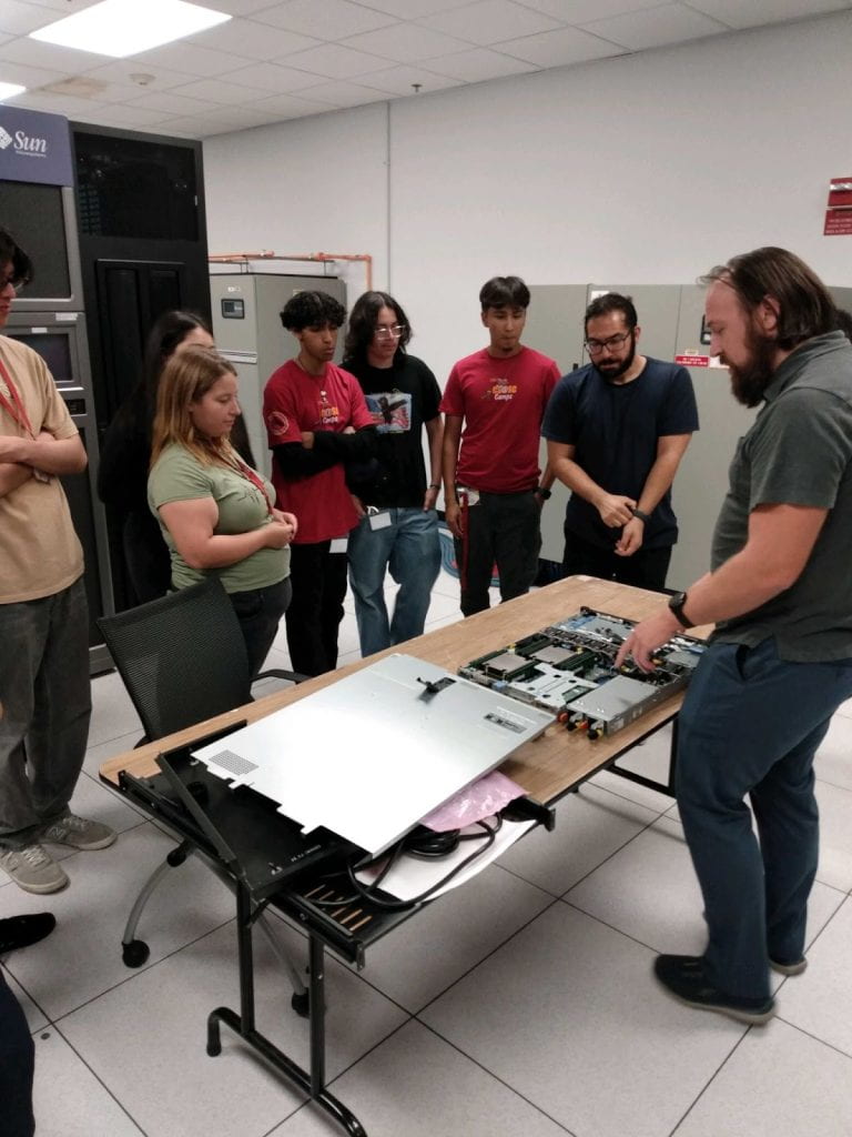 Students circling around a disassembled computer.